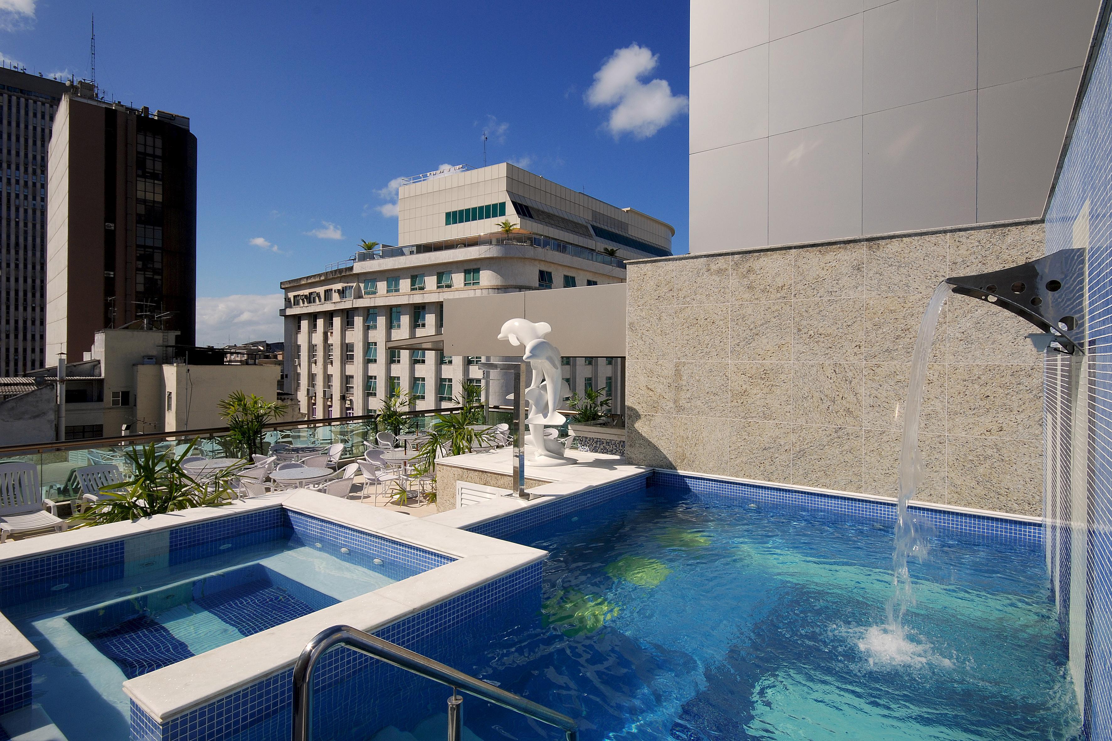 Hotel Atlântico Business Centro Rio de Janeiro Exterior foto The photo shows a rooftop area featuring a swimming pool and a spa. The pool is inviting with a clear blue water, and there appears to be a waterfall feature. Surrounding the pool are areas for relaxation, possibly with sun loungers. In the backgroun